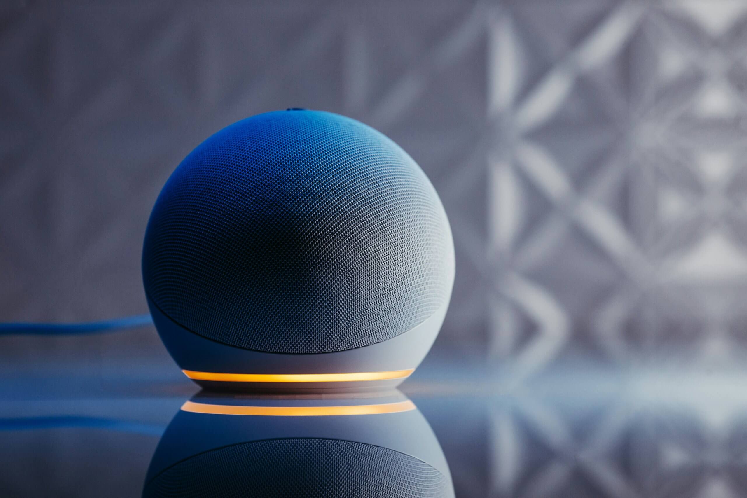 A spherical Amazon Echo smart speaker with its light ring glowing orange
